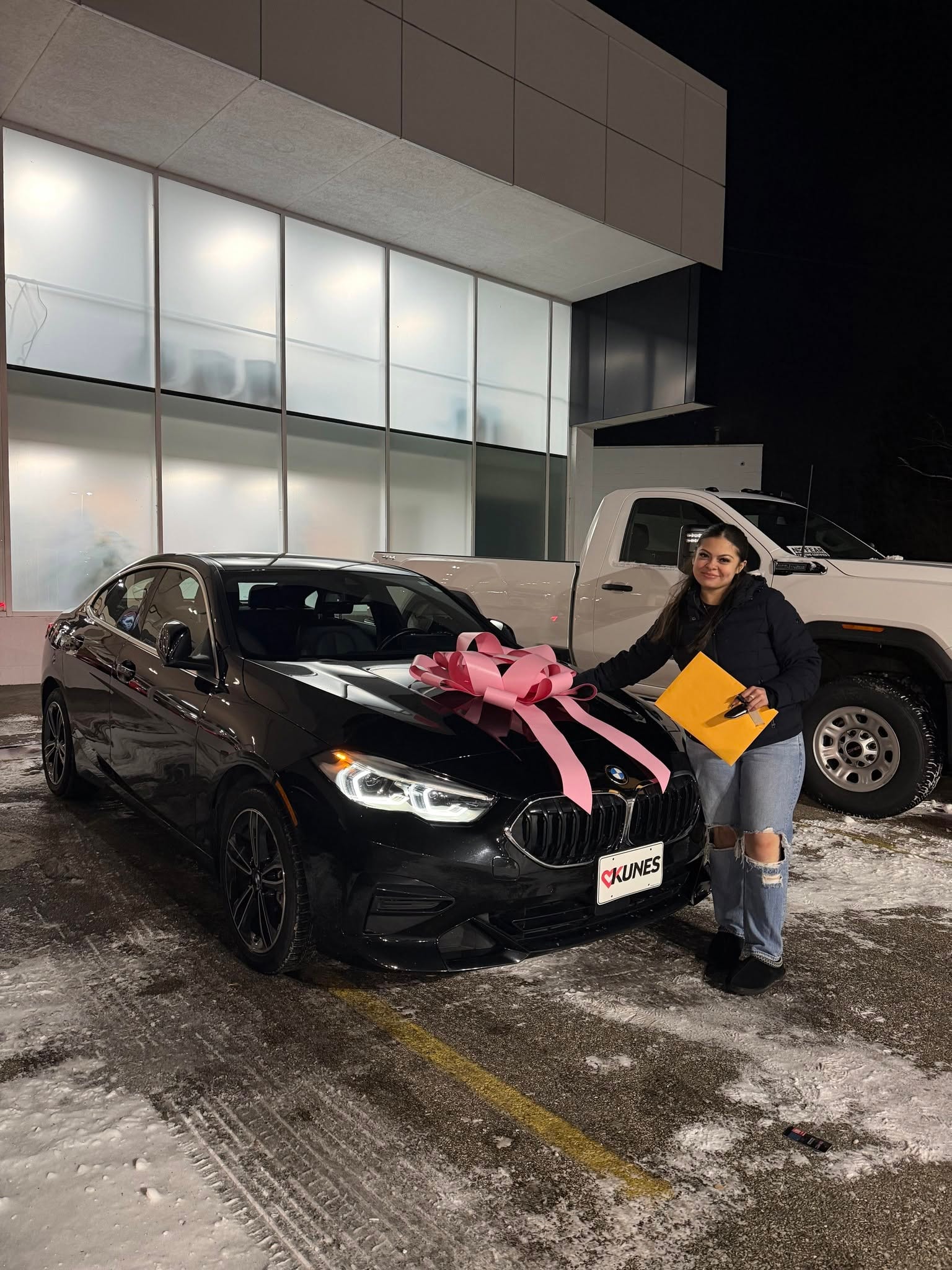 Customer posing with her new black car with pink bow